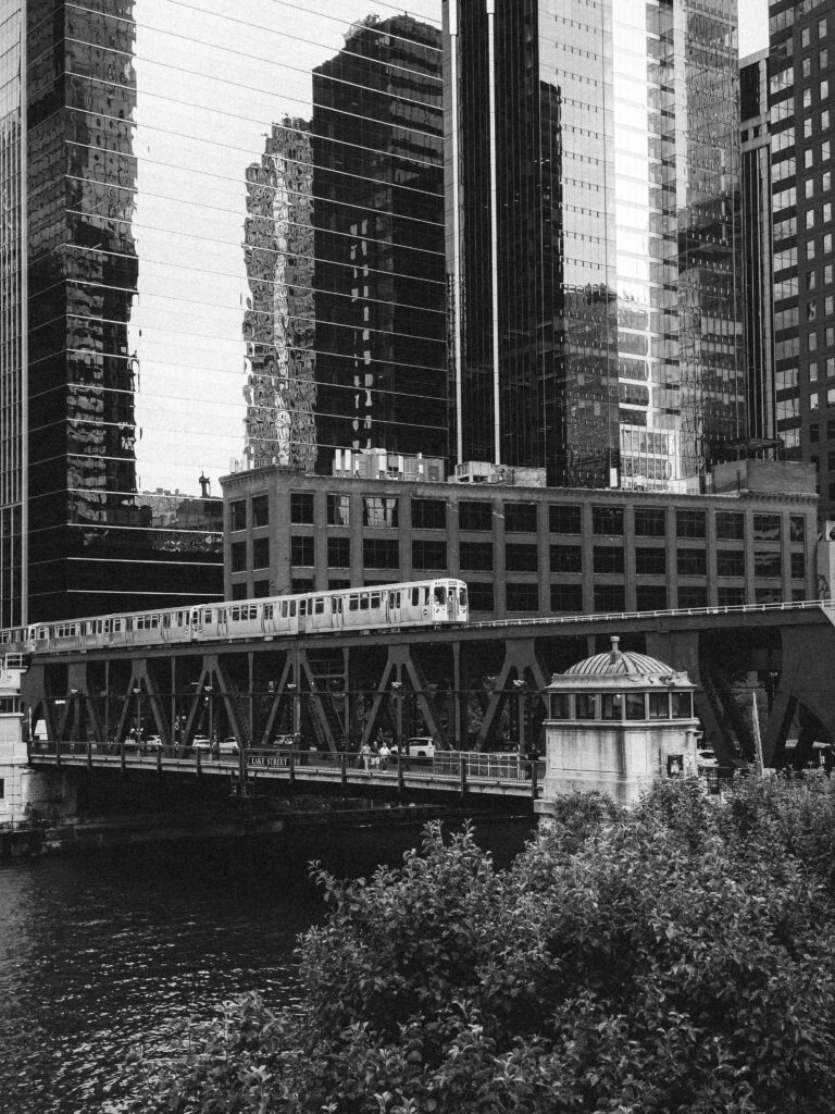 A monochrome image of a train crossing a bridge in downtown Chicago, USA.